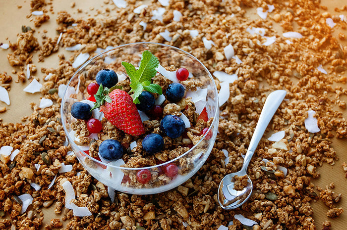 Knuspriges Granola mit Kokosnuss und frischen Beeren getoppt