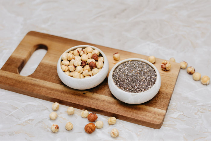 Natürliche Haselnüsse und knusprige Chisamen in Schüssel auf einem Holzbrett